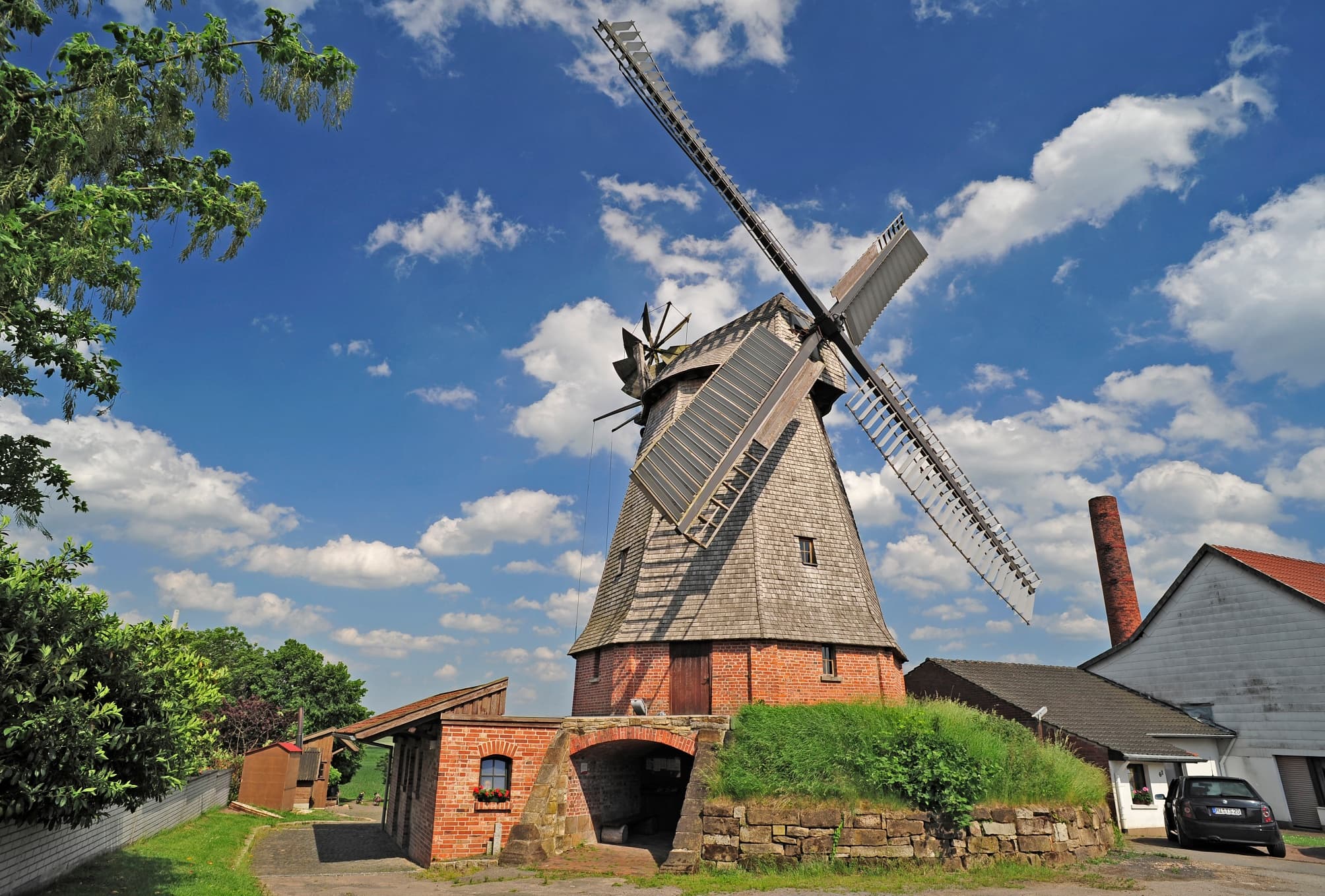 Historische Windmühle aus Backstein und Holz in ländlicher Umgebung mit malerischem Himmel im Hintergrund.